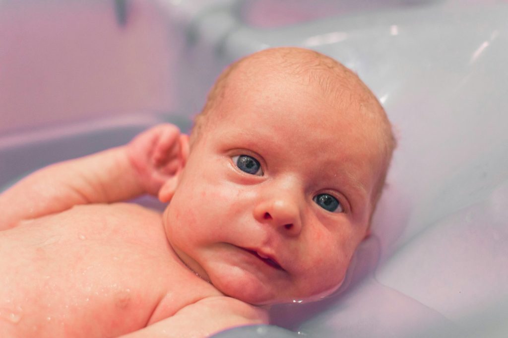 baby lying on white bathtub